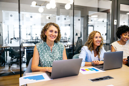 Diverse businesswomen working, collaborating, and discussing projects in a contemporary coworking space, fostering teamwork and innovation