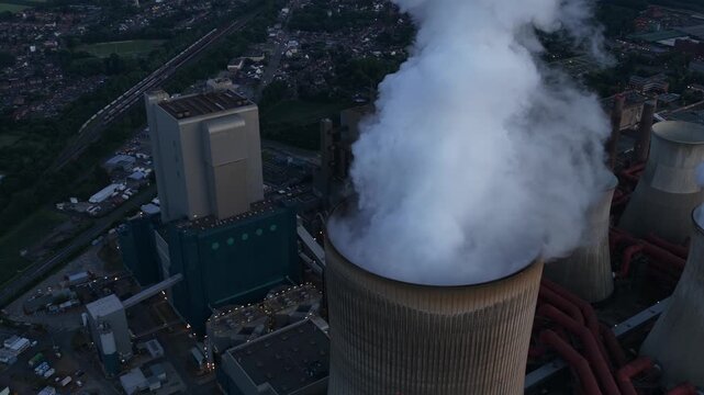 Aerial view of Power Plant Niederausem in Germany at dusk, showing a massive fossil fuel station with smoking cooling towers and industrial energy infrastructure.