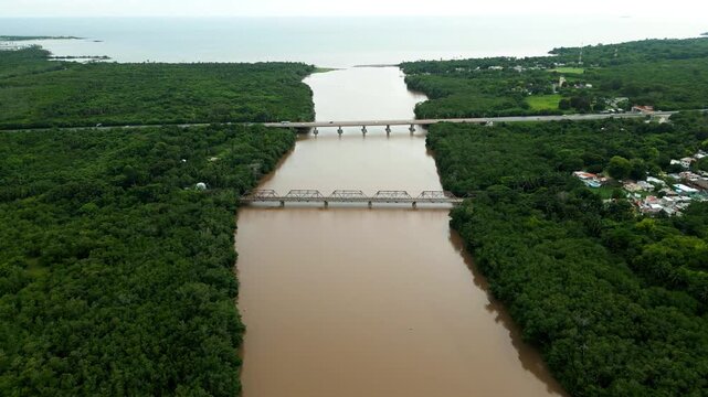 Aerial view of Rio Soco flowing through dense tropical vegetation with two bridges crossing the river in San Pedro de Macoris, San Pedro de Macoris, Dominican Republic.