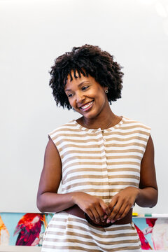 Black businesswoman expressing happiness and creativity in a modern coworking office environment, showing a positive attitude