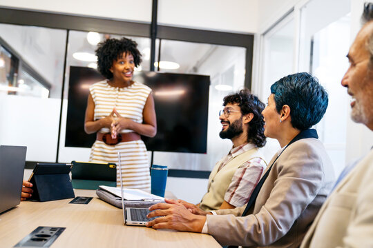 Woman presenting to a diverse group of professionals collaborating in a coworking space during a business meeting