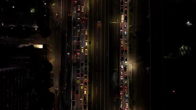 Aerial view of heavy traffic on a multi-lane highway at night with illuminated vehicle headlights and taillights in Jakarta, Indonesia.