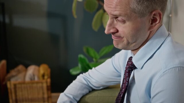 Middle-aged Caucasian man fidgeting with hands nervously and talking during therapy session. Footage is ideal for mental health awareness campaigns and psychological counseling services