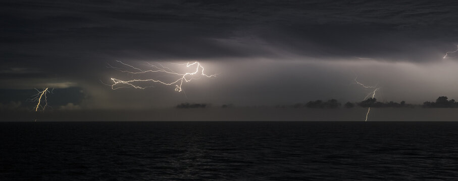 Severe weather and climate change, lightning storm over dark ocean at night
