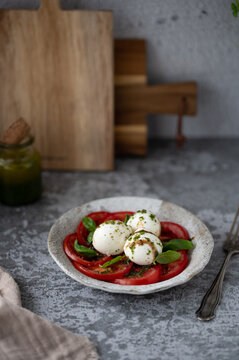 Fresh Caprese salad with tomatoes, mozzarella and basil on rustic plate