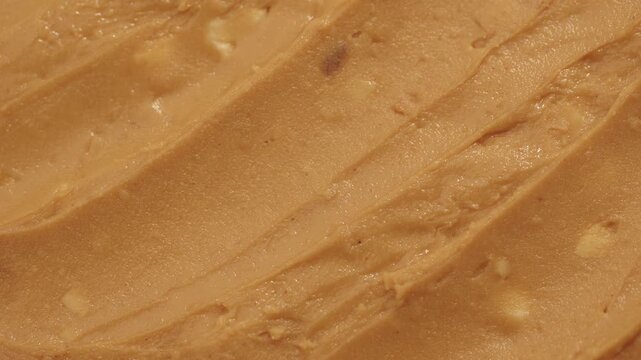 Peanut butter texture circle rotation close up top view. Crunchy peanut butter with peanut pieces. Classic peanut butter.