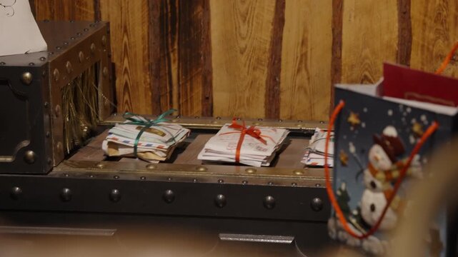 Bundles of Christmas mail and letters tied with ribbons move along a vintage conveyor belt into a sorting machine inside Santa Claus workshop