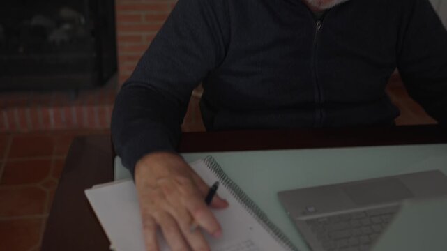 Mature man with glasses writing notes at home office desk