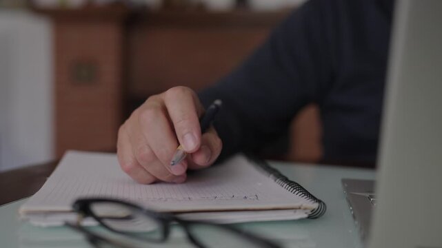 Stressed man tapping pen on notepad while thinking