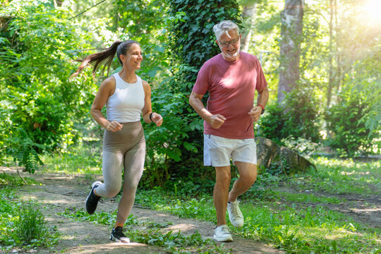 Senior man participating in an outdoor running session with a fitness coach to enhance cardiovascular health, stamina, functional fitness, and overall physical well-being.