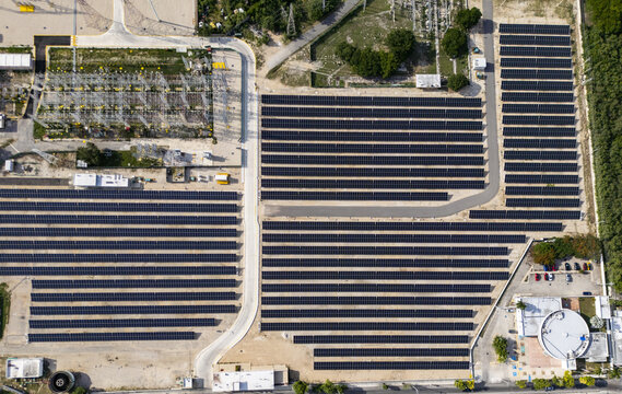 Aerial view of a large solar power plant with rows of photovoltaic panels, electrical infrastructure, and surrounding vegetation in Merida, Yucatan, Mexico.