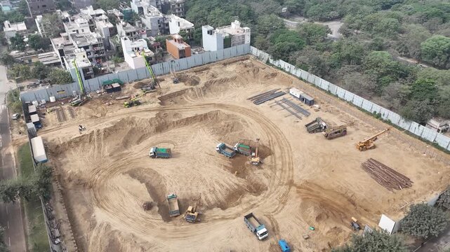 Aerial view of a construction site with excavators and dump trucks working on the ground in Noida, Uttar Pradesh, India.