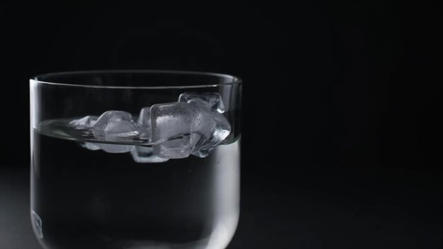 Sparkling ice water glass minimal background with clear liquid cube cold drink on black background calm mood freshness concept cool refreshment feeling transparent purity clean beverage