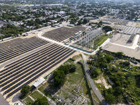 Aerial view of a solar power plant featuring rows of photovoltaic panels and an electrical substation, situated within the urban landscape of Merida, Yucatan, Mexico.