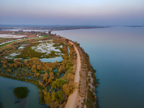 Aerial view of Qadirabad Head Works Bridge spanning the Chenab River with surrounding wetlands, lush vegetation, and a dirt road in Wazirabad, Punjab, Pakistan.