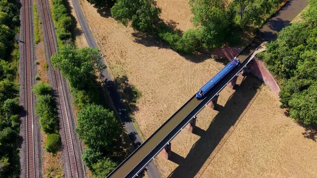 Aerial view of Edstone Aqueduct with a narrowboat crossing the canal alongside railway tracks in Wootton Wawen, England, United Kingdom.