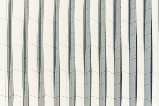 Close-up abstract pattern of tapered white facade ribs creating a rhythmic, minimalist geometric texture across the surface.