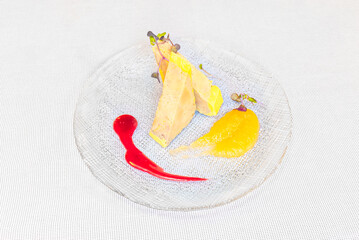 Elegant foie gras terrine with mango puree and berry coulis, artfully plated on a textured glass dish. © Toyakisfoto.photos