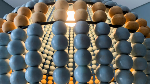 Abstract architectural installation featuring numerous blue, gold, and beige spherical elements arranged in a dense three-dimensional geometric pattern. The repeating spheres create depth, texture
