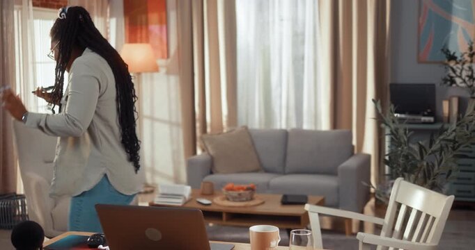 Frustrated Black woman argues during a phone call while pacing in her living room and working from home.