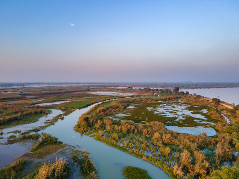 Aerial view of the Chenab River wetlands near Qadirabad Head Works Bridge, featuring winding waterways, lush vegetation, and calm water in Wazirabad, Punjab, Pakistan.