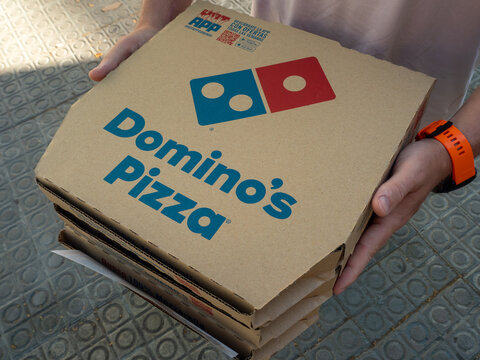 person holding stack dominos pizza boxes delivery takeaway outdoor