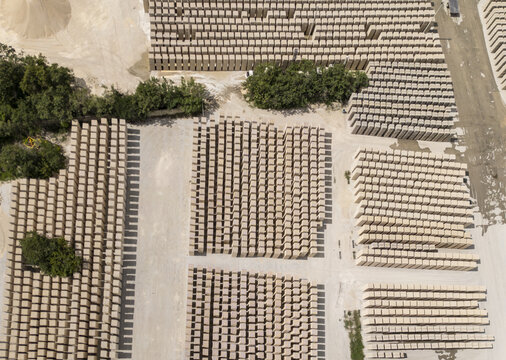 Aerial view of a brick factory with organized rows of stacked clay bricks, surrounding trees, and dirt ground in Merida, Yucatan, Mexico.