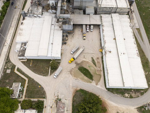 Aerial view of corn flour factory with parked semi-trucks, industrial buildings, and a dirt yard in Merida, Yucatan, Mexico.