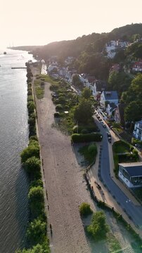 Aerial view of Elbstrand Blankenese along the Elbe river with sandy beach, lush trees, and residential houses in Hamburg, Hamburg, Germany.