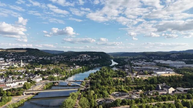 Drone aerial panorama of Konz, Germany, featuring the Saar River approaching its confluence with the Moselle, road bridges, residential neighborhoods, green hills and the surrounding river valley. Sce