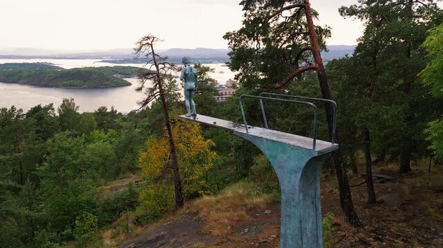 Aerial view of the statue on a diving board in Ekebergparken overlooking the Oslofjord with surrounding pine trees and coastal landscape in Oslo, Oslo, Norway.