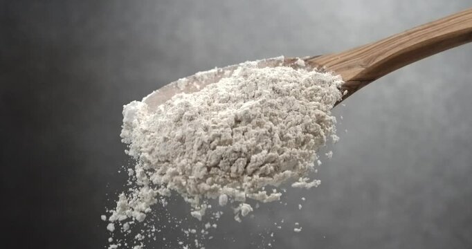 Flour falling from wooden spoon in super slow motion