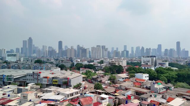 Aerial view of the Jakarta skyline rising above dense residential rooftops and urban sprawl in Jakarta, Indonesia.