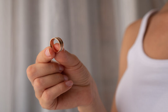 Woman holding wedding rings after divorce, broken marriage and heartbreak.