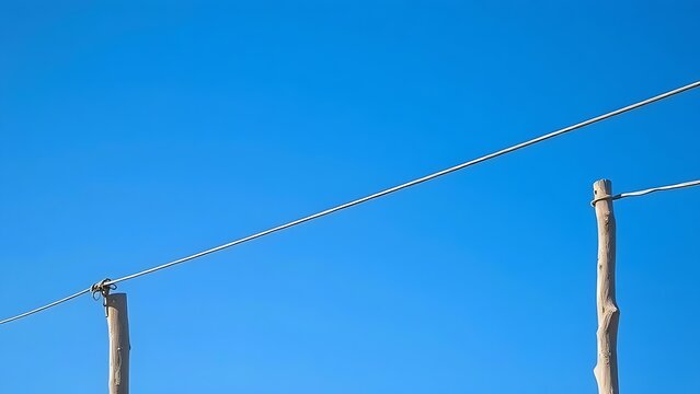 Tightrope wire between wooden poles with balancing pole, balance and risk concept.