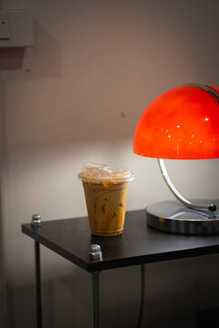 Close up and selective focus glass of ice latte caramel on black table with orang lamp at coffee shop.