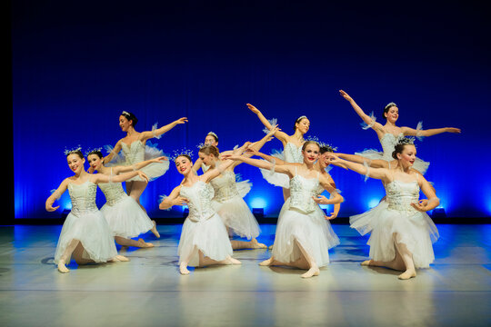 Ballet dancers perform an elegant group dance in white tutus on stage