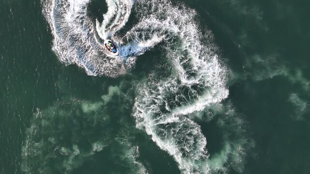 Aerial view of a jet ski carving a wake in the dark blue ocean water Cascais, Lisboa, Portugal.