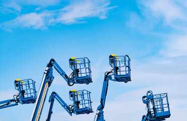Articulated boom lift fleet with telescopic aerial work platforms against sky. Construction equipment rental, industrial maintenance, hydraulic access systems, engineering services and elevated work. © Fahroni
