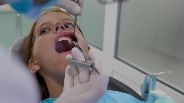 Pediatric dentist giving local anesthesia injection to young girl patient.