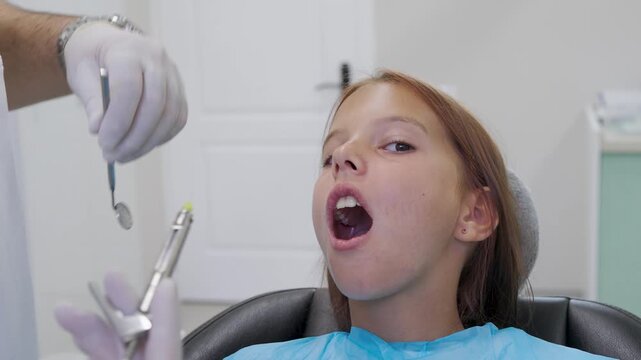 Pediatric dentist giving local anesthesia injection to young girl patient.