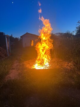 a large evening bonfire against the backdrop of the darkening day