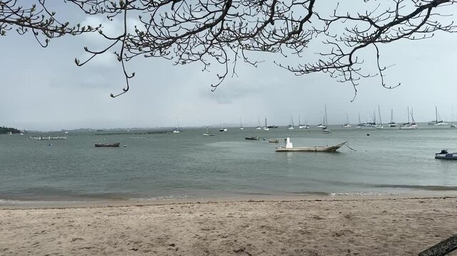 Static shot of Sambaqui Beach in Florian&oacute;polis, Brazil, featuring calm waters, anchored fishing boats and a peaceful waterfront under natural daylight.