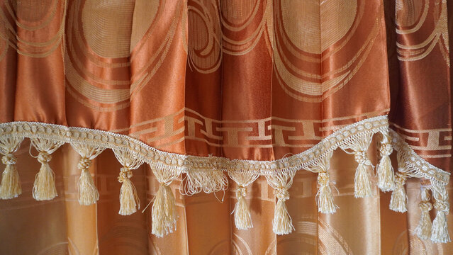 Elegant curtain with ornamental tassel fringe and circular pattern.