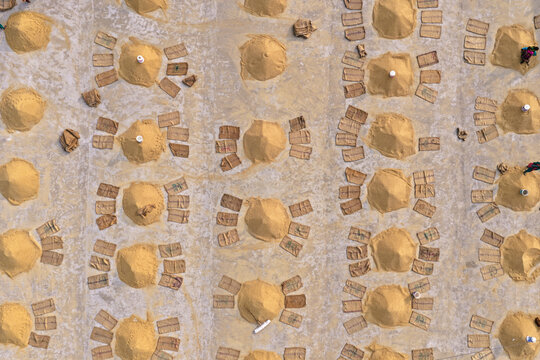 Aerial view of rice piles drying on the ground with workers in Ashuganj, Chittagong Division, Bangladesh.