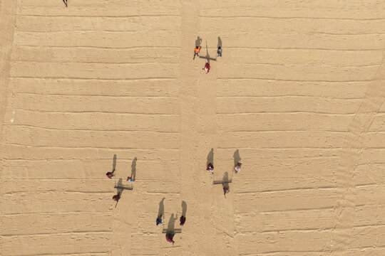 Aerial view of workers raking and spreading grain on a large drying floor in Ashuganj, Chittagong Division, Bangladesh.