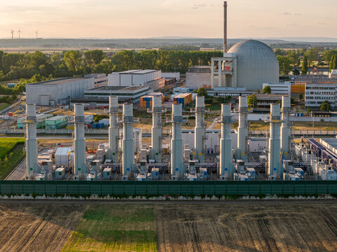 Aerial view of the Gaskraftwerk Biblis BNBM power plant with multiple exhaust stacks and the reactor dome in the background during golden hour in Biblis, Hessen, Germany.
