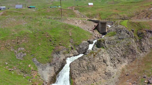 Mountain waterfall Chirukhi cascades in aerial view through a concrete culvert into a rocky gorge, supporting Georgian travel, freshwater resources, highland infrastructure and environmental geography