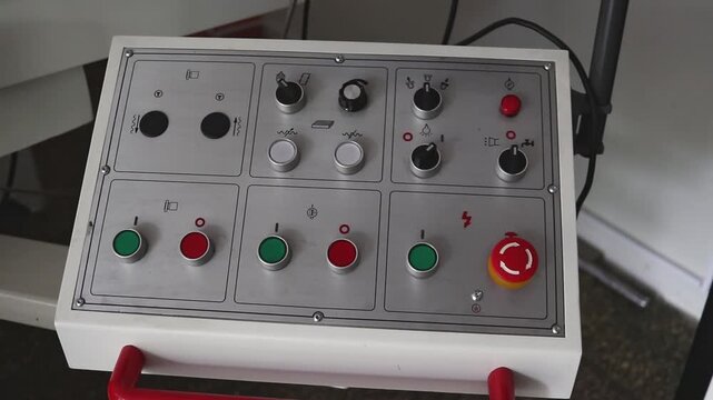 Close-up of the machine control panel. Buttons, switches and an emergency button for starting, stopping and adjusting the equipment.