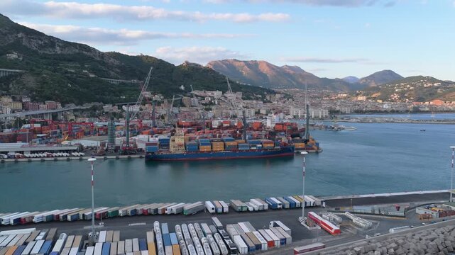 Salerno, Italy - 25 July 2026: Aerial view of the busy commercial port with container ships, cranes, and rows of parked semi-trailers along the waterfront in Salerno, Italy.